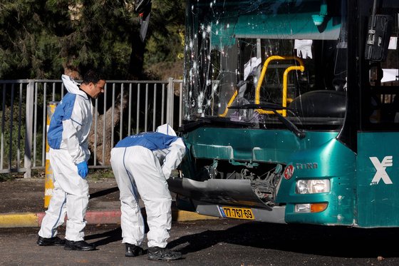 이스라엘 경찰이 23일 예루살렘의 버스정류장에서 폭발사고로 파괴된 버스를 살피고 있다. 로이터=연합뉴스